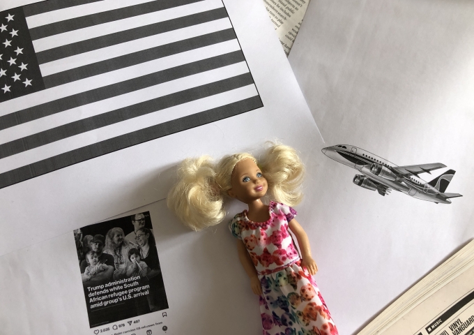 Schwarz-Weiße Collage zeigt eine weiße lächelnde Puppe in geblümtem Kleid, die auf sich überlappenden Ausdrucken liegt, von denen einer die amerikanische Flagge angeschnitten zeigt, sowie ein generisches Flugzeug und die Schlagzeile einer Newsmeldung auf Englisch