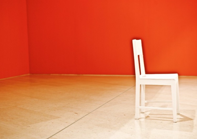 A solitaire white chair in a room with red walls