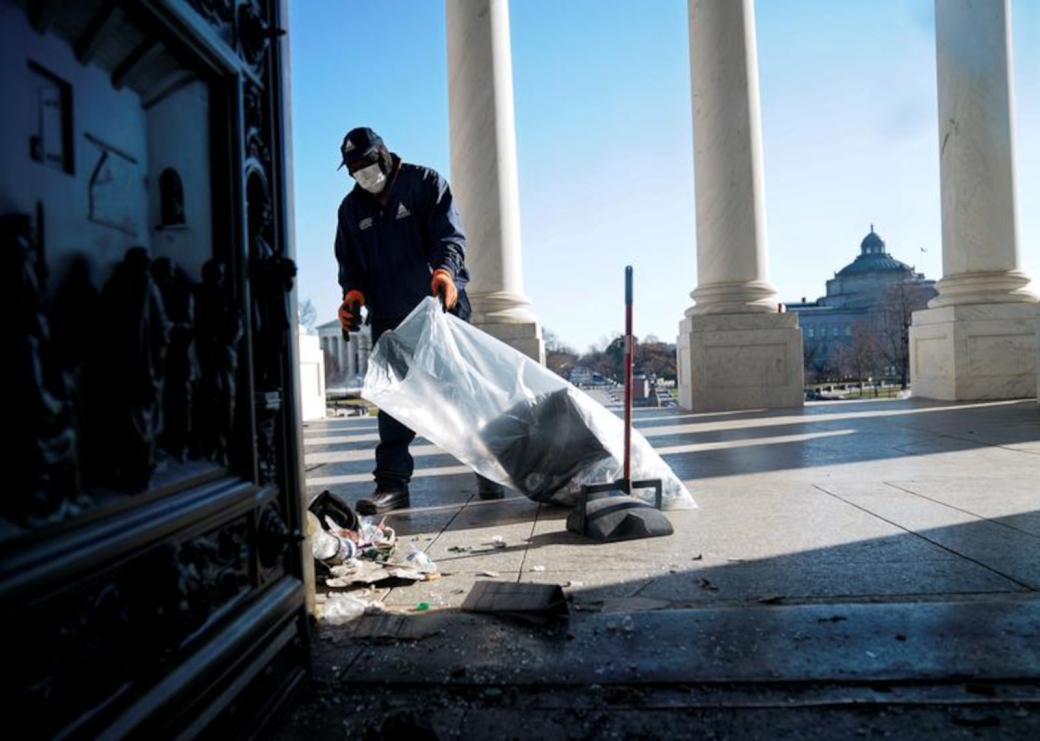 A worker cleans up debris outside the U.S. Capitol a day after supporters of President Trump stormed the building.
