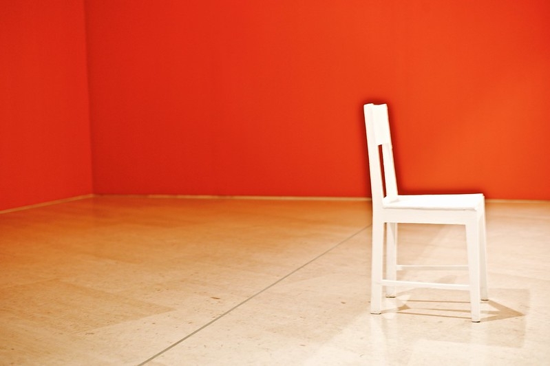 A solitaire white chair in a room with red walls